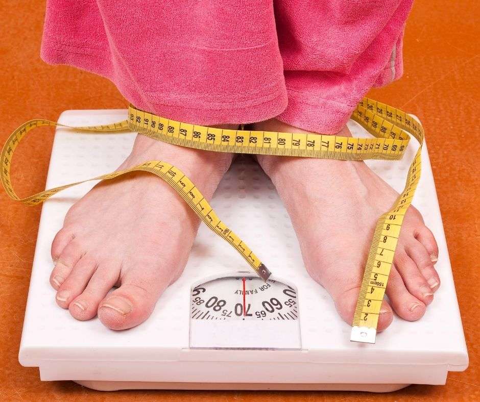 woman standing on scales with tape measure