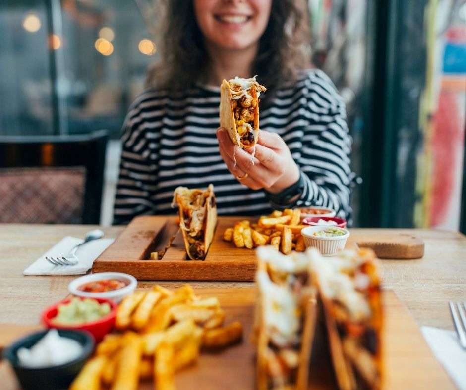 woman eating tacos and fries